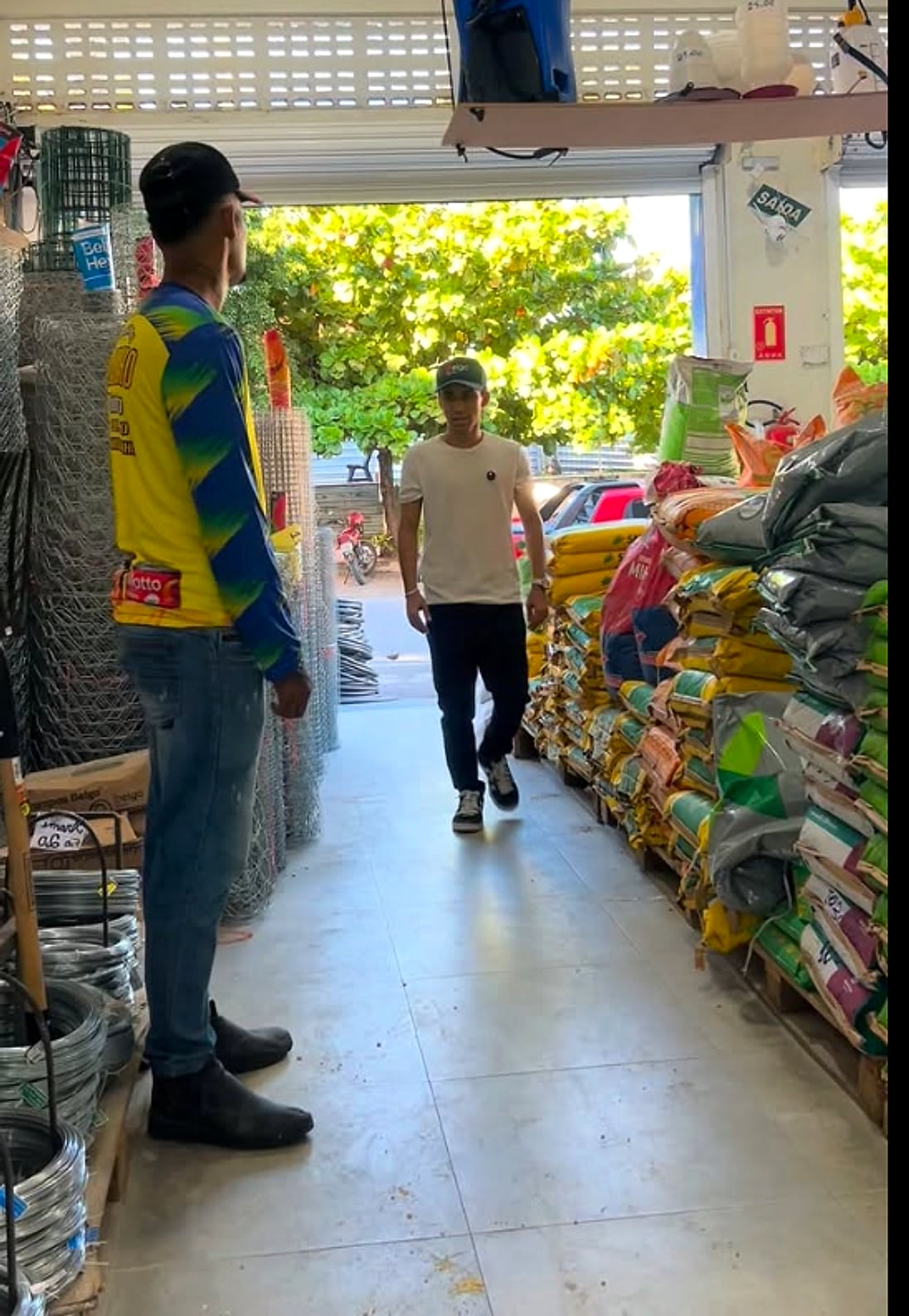 Corredor da loja com rolos de tela e sacos de ração